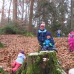 Waldspiele im Herbst, Kinder auf einem Baumstumpf.