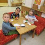 Drei Kinder beim Spiel mit Play-Doh und Kaffeetabletten in einem Kindergarten.