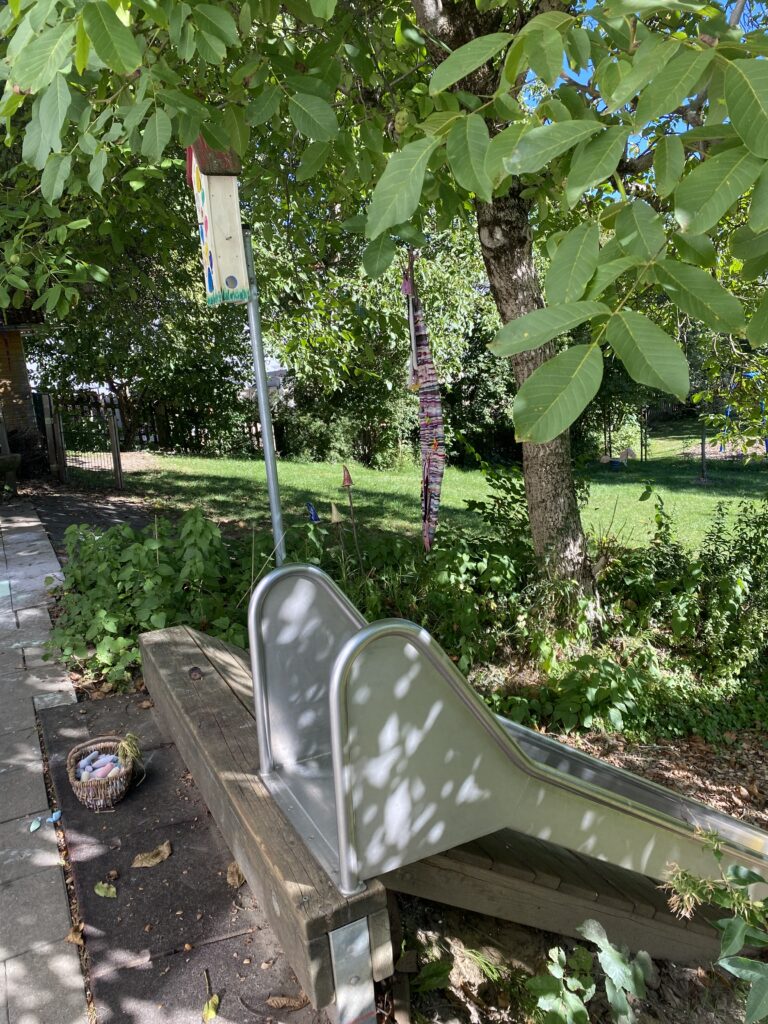 Rund um einen Spielplatz mit Schaukel, Regenschirm und einer Kiste.