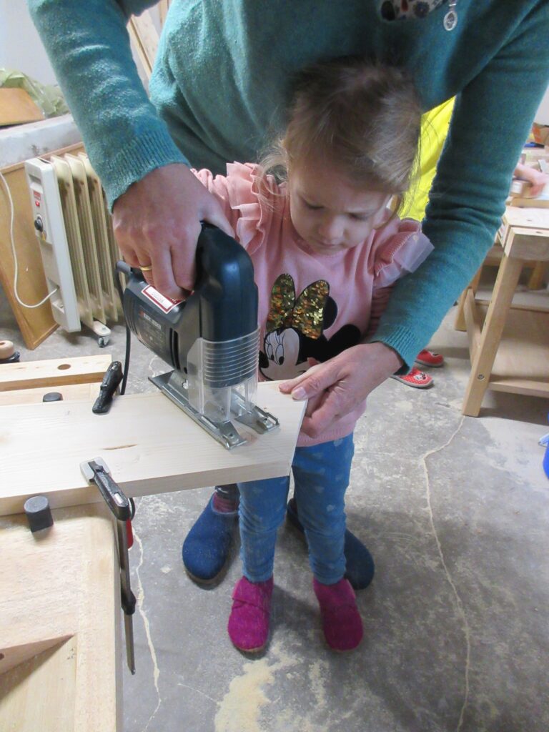 Mutter und Tochter arbeiten gemeinsam an einer Holzmaschine.