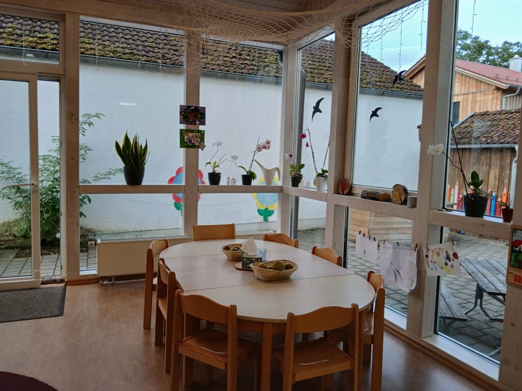 Küchenbereich mit Tisch, Stühlen und Pflanzen im Innenraum.