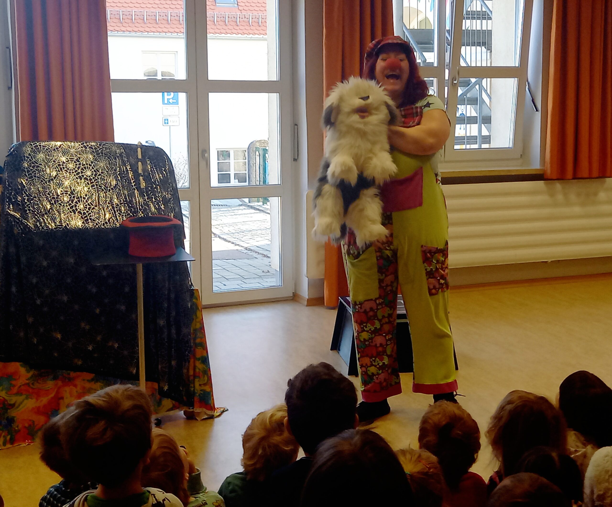 Kinder mit Clown und Puppenspieler im Raum.