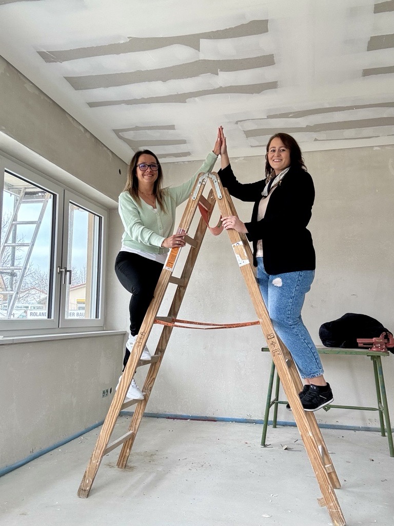 Zwei Frauen auf einer Leiter in einer Baustelle