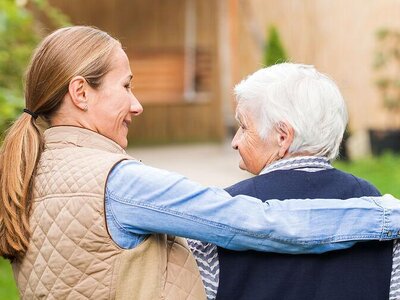 Eine junge Frau nimmt eine ältere Frau in den Arn.